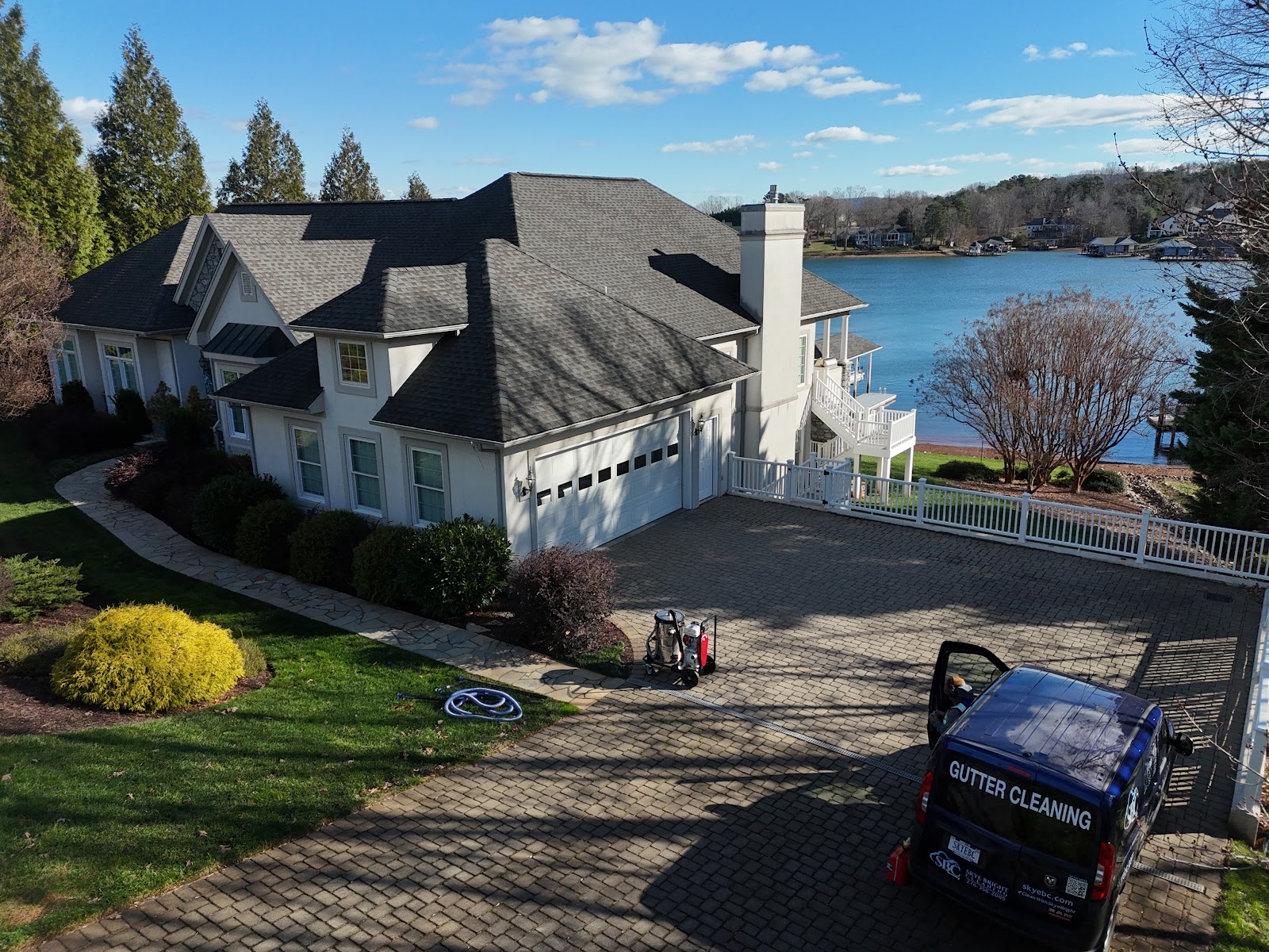 Skye Bright Cleaning blue wrapped van at a lakefront home gutter cleaning job